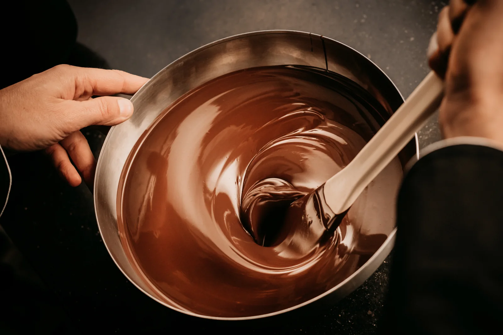 Melted chocolate being stirred in a metal bowl